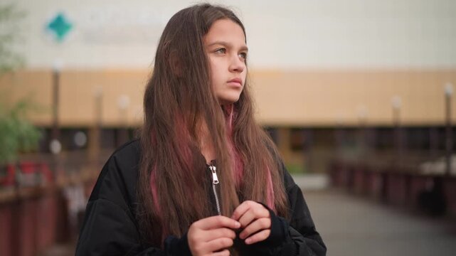 Reflective woman standing on rainy city street. Contemplative young woman with damp hair in urban setting. Girl with pinktipped damp hair on rainy city sidewalk displaying introspective mood