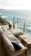 Fototapeta premium Luxury outdoor living space with comfortable sofa and coffee table overlooking a stunning ocean view with rocky coastline and blue sea water on a clear day