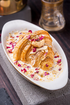 oum ali dish served in an oval bowl topped with an edible rose and cashew nuts