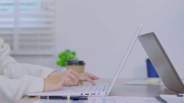 The focused hands typing on a laptop in a modern workspace. 