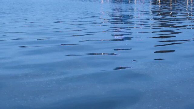Silent rippling lake surface with building and light reflections, abstract water background footage