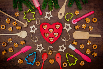 Naklejka premium Cookies and baking tools are arranged around a heart-shaped tray with festive decorations during a holiday season activity