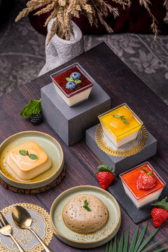 a group of desserts such as strawberry pana cota, mango pana cota, blueberry pana cota, sugar apple pudding and also caramel pudding which are served and arranged perfectly