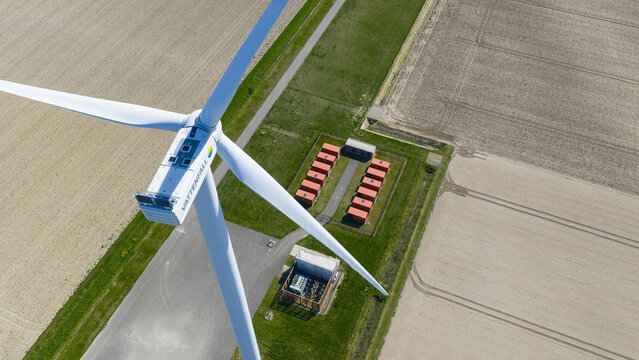 Aerial view of a Vattenfall wind turbine and a battery storage facility with red containers in the agricultural fields of Middelharnis, Zuid-Holland, Netherlands.
