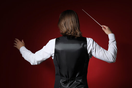 Male conductor on red background, back view