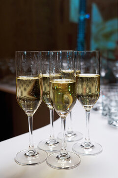 Close-up of champagne glasses with bubbles on a white table. Elegant celebration, banquet, or wedding reception scene