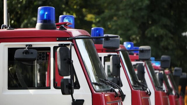 Fire trucks with blue emergency lights parked in a row, ready to respond