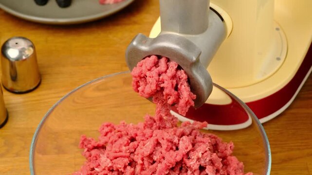 Making ground beef using an electric meat grinder on a wooden table. Step-by-step video recipes. Horizontal video.