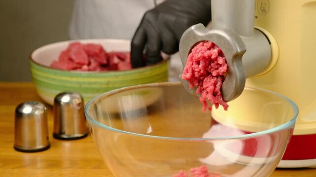 Making ground beef using an electric meat grinder on a wooden table. Step-by-step video recipes. Horizontal video.
