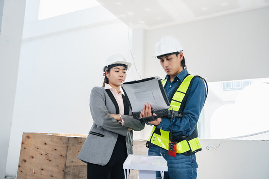 Professional engineer and businesswoman discussing a solar energy project at an indoor construction site