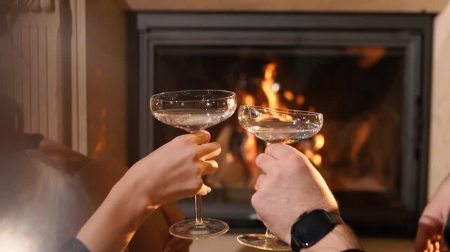 A loving couple on a date drinking an alcoholic cocktail near a fireplace. A man and a woman are having a romantic dinner. A close-up of a glass goblet of champagne. Sparkling wine with reflections
