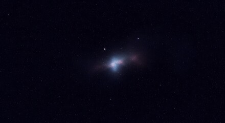 Obraz premium A distant galaxy with a bright core and surrounding nebulosity, set against a dark, star-filled sky.