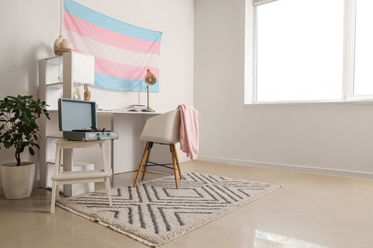 Interior of light room with workplace and transgender flag