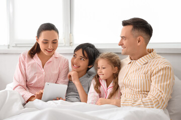 Fototapeta premium Little children with their parents using tablet computer in bedroom