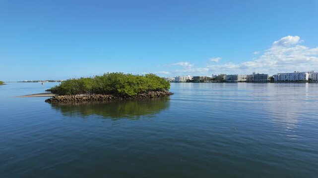 Panning shot taken from Snook Island Boardwalk shows small island blue sky and distant waterfront property.