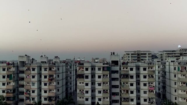 People flying kites from apartment rooftops during Makar Sankranti in an Indian city. Perfect for festival campaigns, cultural storytelling, community lifestyle, and urban celebration visuals.