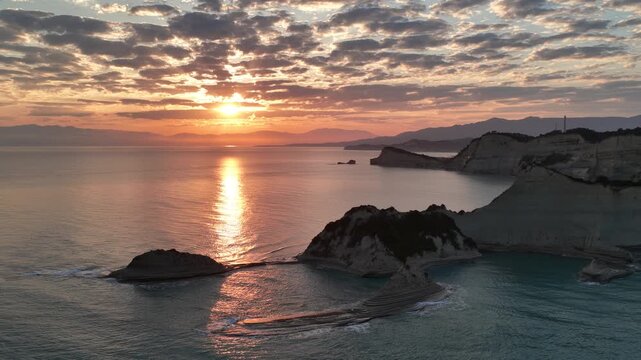 Aerial flight over beautiful small islets and rugged coastline of Cape Drastis during a spectacular morning sunrise over the Ionian Sea in Corfu Greece, stunning nature scenery
