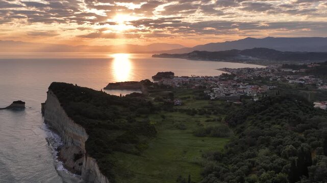 Aerial panoramic view of Sidari town and coastline at sunrise, golden sun rays over the Ionian Sea, beautiful clay cliffs of Corfu island, Greece
