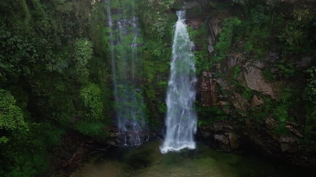 Th&aacute;c Ti&ecirc;n waterfall mid-wide aerial showing the pool and rock formations at the base, enclosed by dense rainforest, Vietnam.