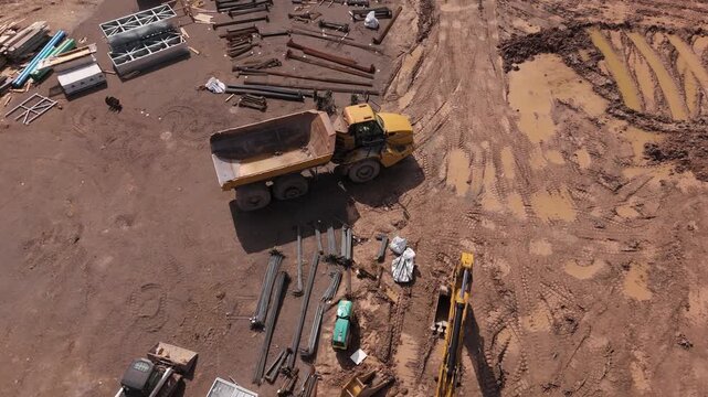 Slow drone flyover construction vehicles and materials sitting on dirt job site