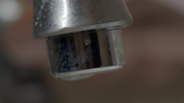 Extreme close up of a dirty bathroom faucet aerator with running water