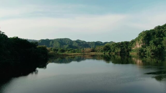 Laguna La Maria, Colima, Mexico reflecting surrounding hills and sky in aerial dolly in view