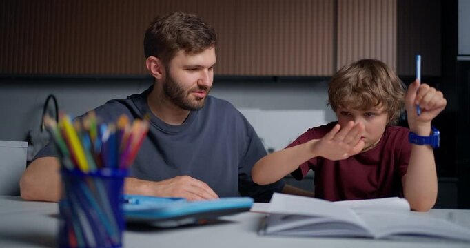 Father Assists Son At Desk. Casual Family Moment Practicing Patience During Educational Activity
