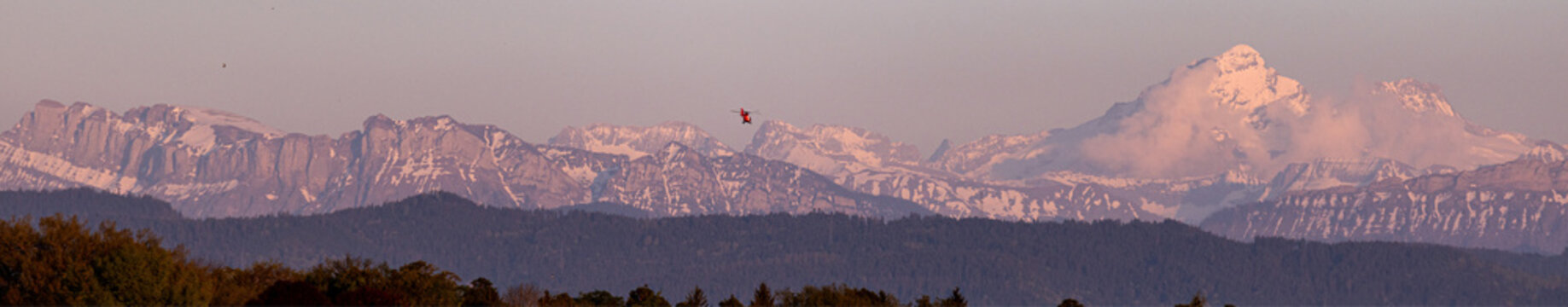 a rescue helicopter heading towards the alps panorama
