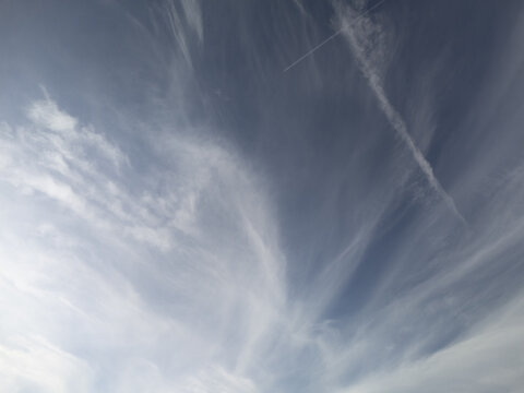 Aerial view of wispy cirrus clouds and a long jet contrail stretching across a clear blue sky Cerin, Banskobystricky kraj, Slovakia.