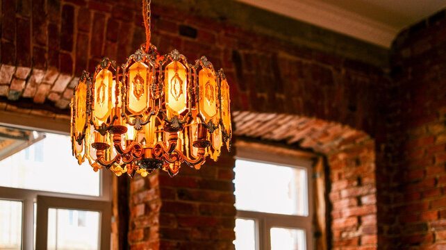 Elegant vintage chandelier with amber glass panels illuminates a rustic brick interior