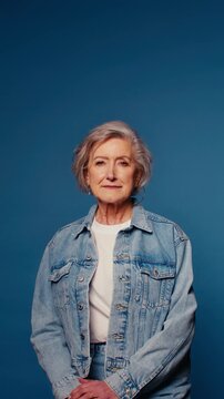 Portrait of a confident senior woman on a vibrant blue backdrop. She exudes wisdom and grace, perfect for projects on aging, empowerment, and active seniors.