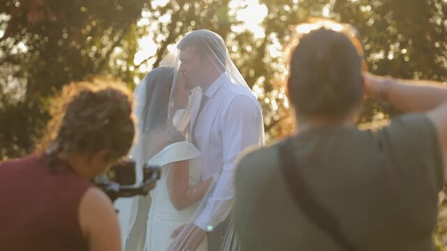 BTS: Wedding photographers snap pictures of bride and groom outside