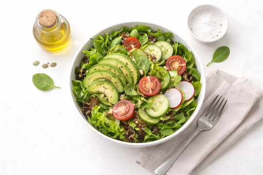 Fresh vegan salad bowl with avocado, cherry tomatoes, and cucumber on white background