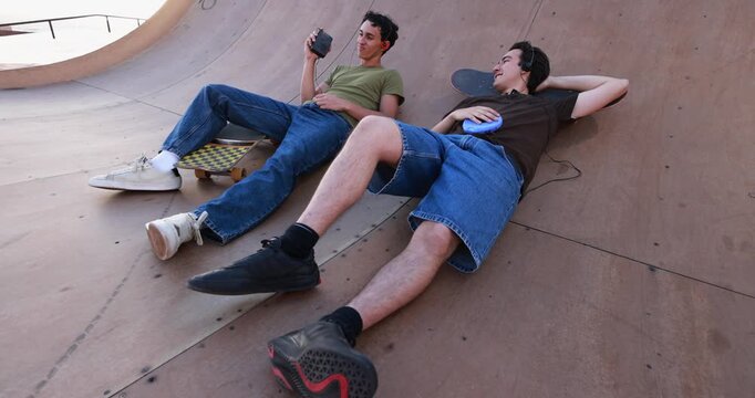 Happy young friends chilling and listening music with cassette and cd player at skateboard park - New trend, people lifestyle and vintage analog devices - UGC wide lens content