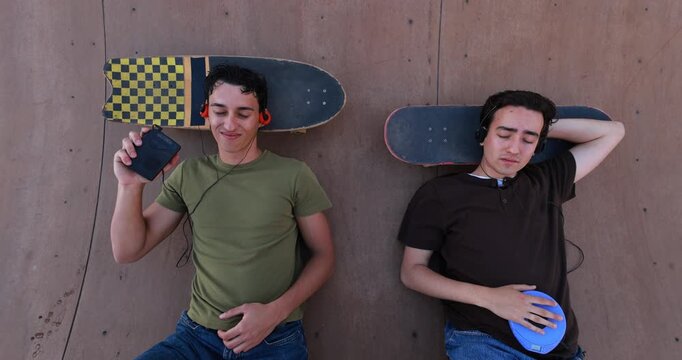 Two young friends listening music with cassette and cd player outdoor - 90's trend, people lifestyle and vintage analog devices - UGC wide lens content 