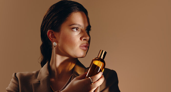 Woman holding perfume bottle in warm editorial portrait