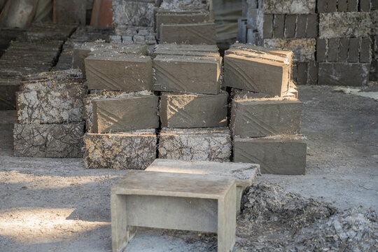 Close-up of raw handmade clay bricks stacked in a traditional village factory. Authentic building materials drying in a rustic outdoor workshop.