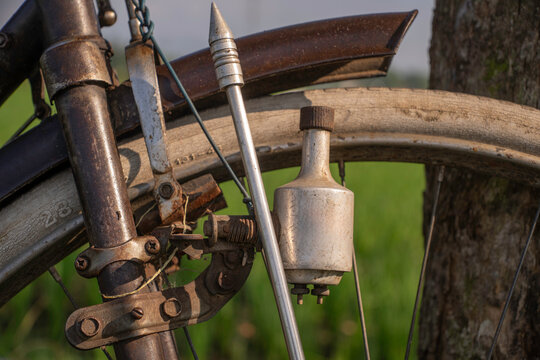 Close-up of a rusty bottle dynamo generator on the front wheel of a vintage classic bicycle.