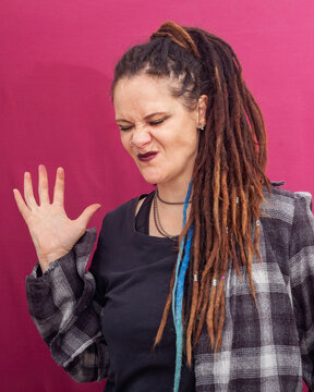 Annoyed woman with dreadlocks making scrunched face on pink background