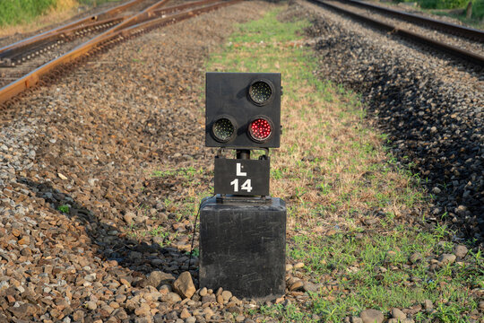 Ground railway signal with lights on a black base at a train track junction. Railway infrastructure and signaling system for safety.