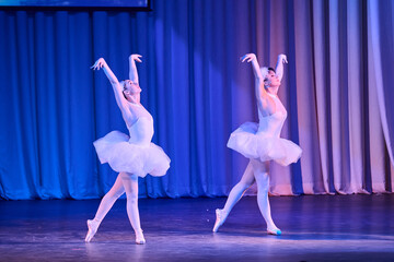 Two ballerinas performing swan lake ballet on stage with blue and purple lighting © TRAVELARIUM