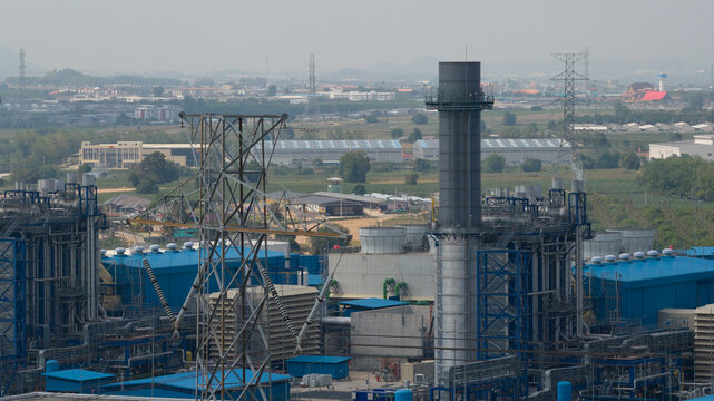 Aerial view of Sriracha Power Plant GSRC featuring industrial chimneys, blue facility buildings, and high-voltage power lines Tambon Khao Khan Song, Chang Wat Chon Buri, Thailand.