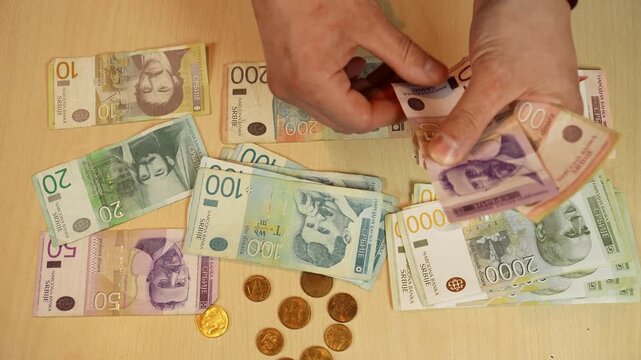 Hands sort Serbian dinar banknotes into separate stacks by value on a table. Cash organization and budget planning concept for finance, savings, accounting and money management
