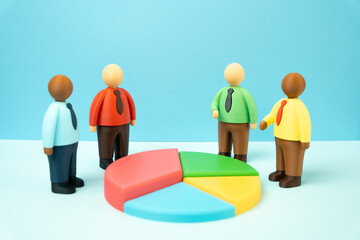 Office workers discuss financial indicators while standing around a pie chart. Data driven...