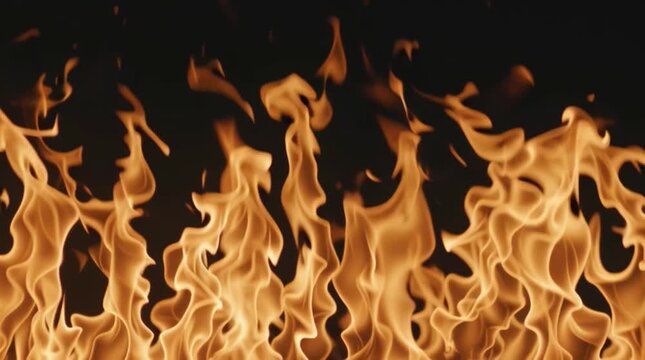 Fire burns brightly in a dark setting with orange and yellow flames moving in different directions during the night