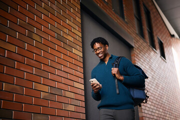 Obraz premium Happy African American student text messaging on mobile phone in city.