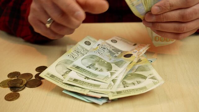 Hands count 2000rsd - Serbian dinar banknotes and coins on a table. Cash handling and expense tracking concept for budgeting, savings, daily spending and personal finance