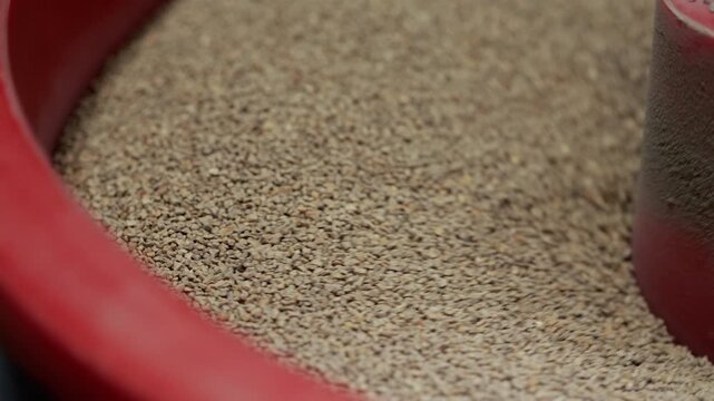 Extreme close-up of fine metal granules or abrasive particles densely packed inside a red bowl, revealing detailed grain texture used in industrial processing or material testing.