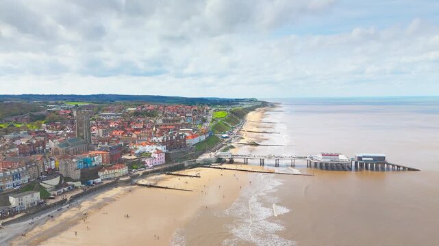 Seaside views of the holiday town of Croma on the Norfolk coast. Sandy beach and sea. Holiday destination, vintage photograph. North Sea coastline, Chapel, church and pier on the promenade, tourists.