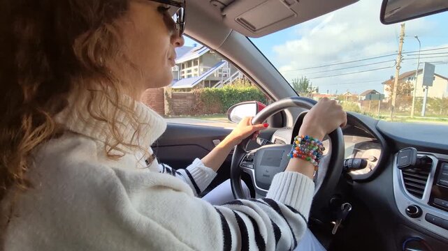 Woman driving car, confident female driver commuting through suburban streets on a sunny autumn day